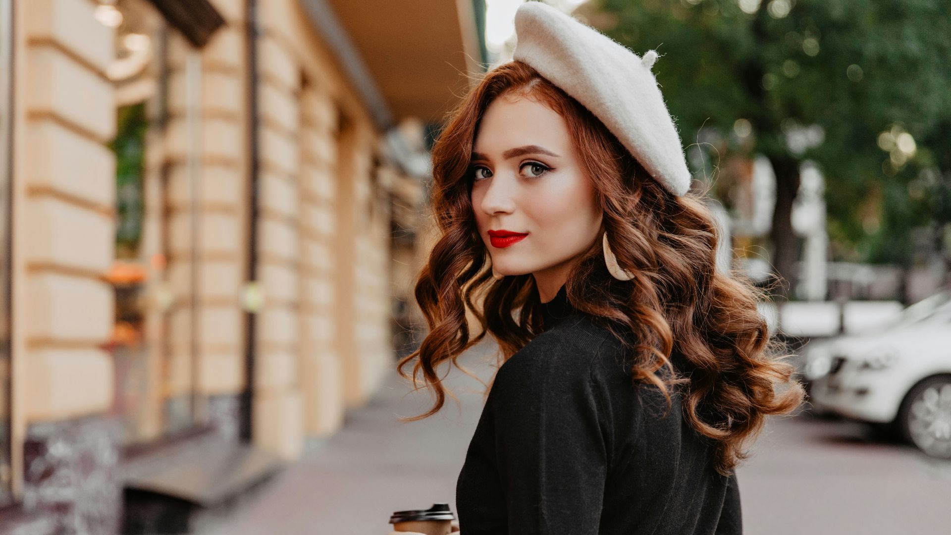 a woman standing on a street holding a cup of coffee