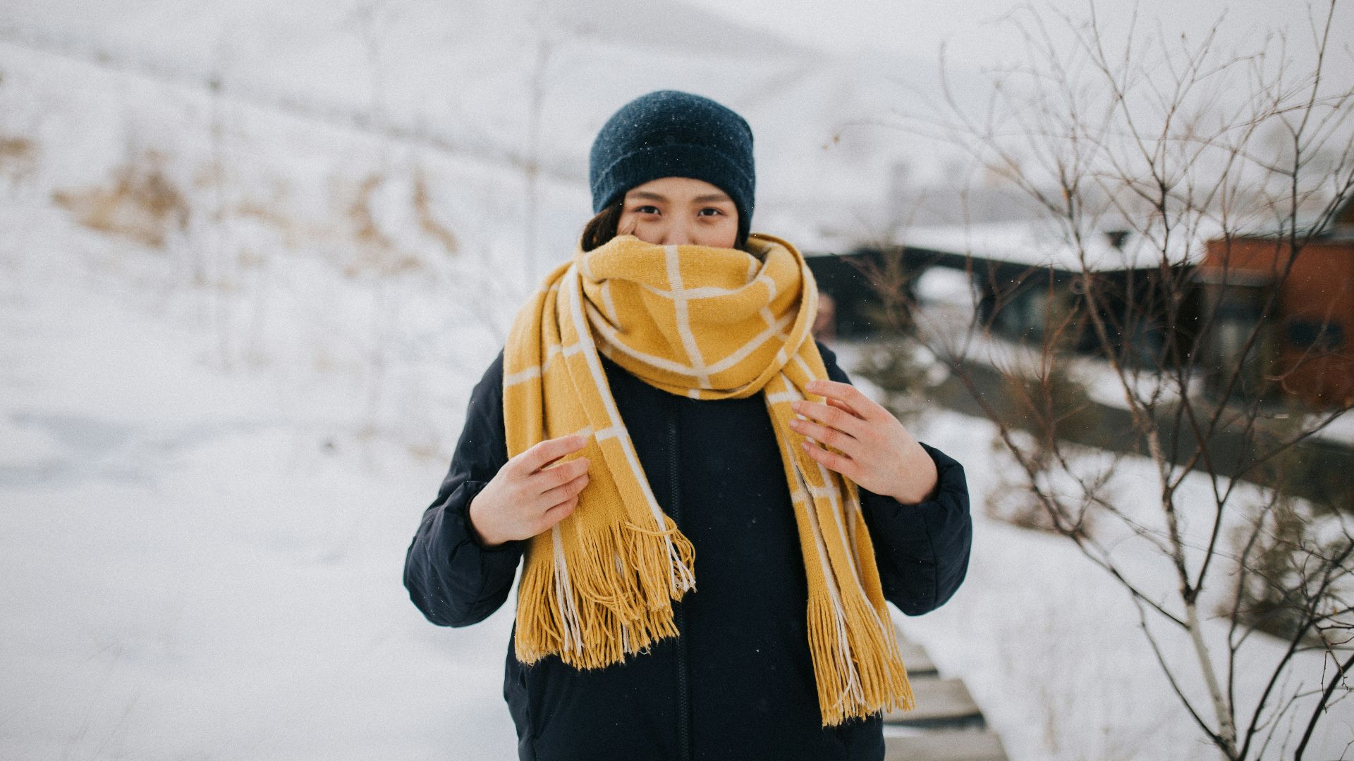 woman in black knit cap and black jacket standing on snow covered ground during daytime