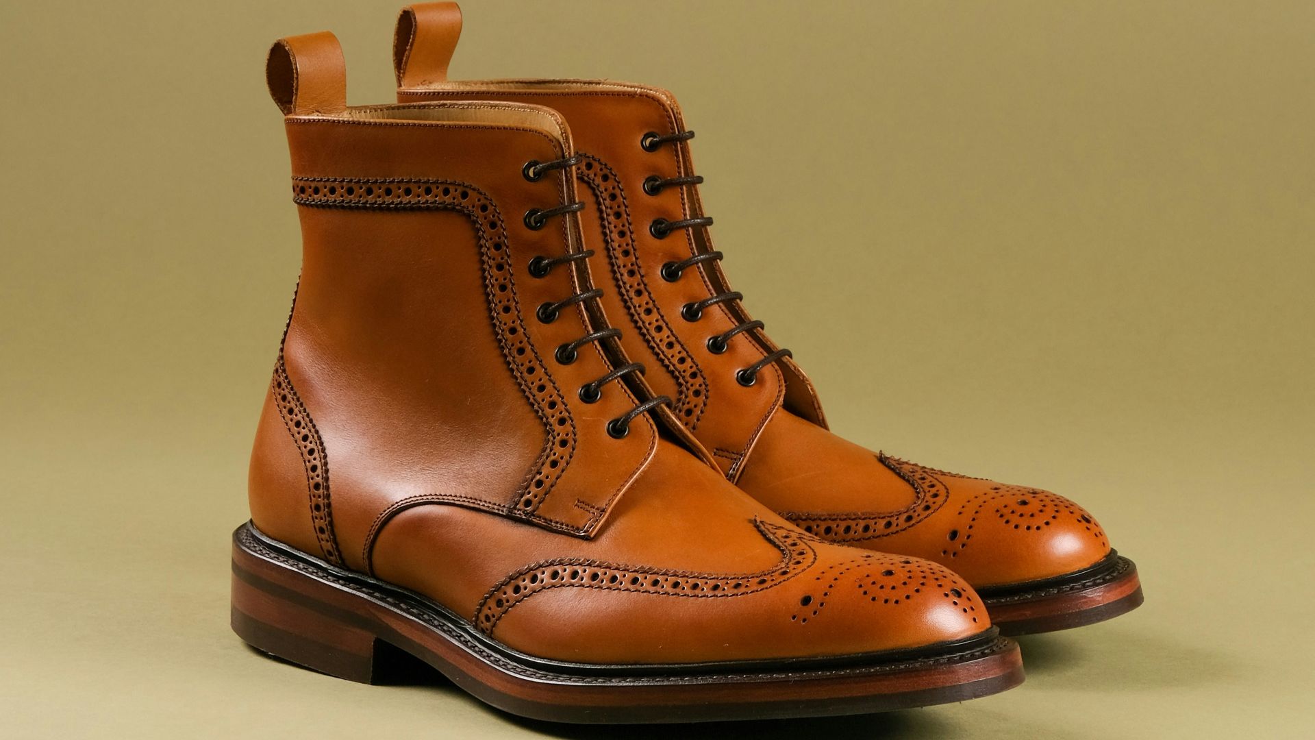 a pair of brown boots with a tan background