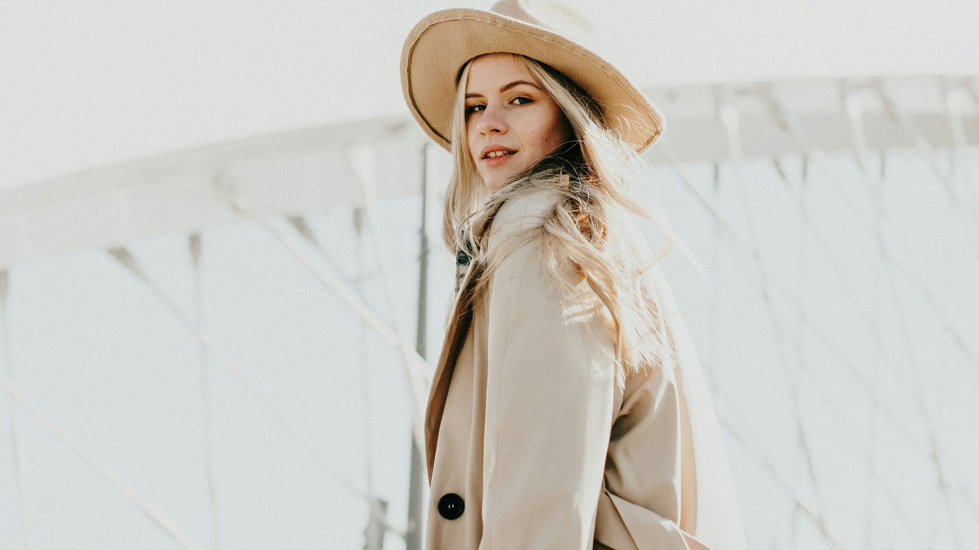 woman in brown coat wearing brown hat standing on snow covered ground during daytime