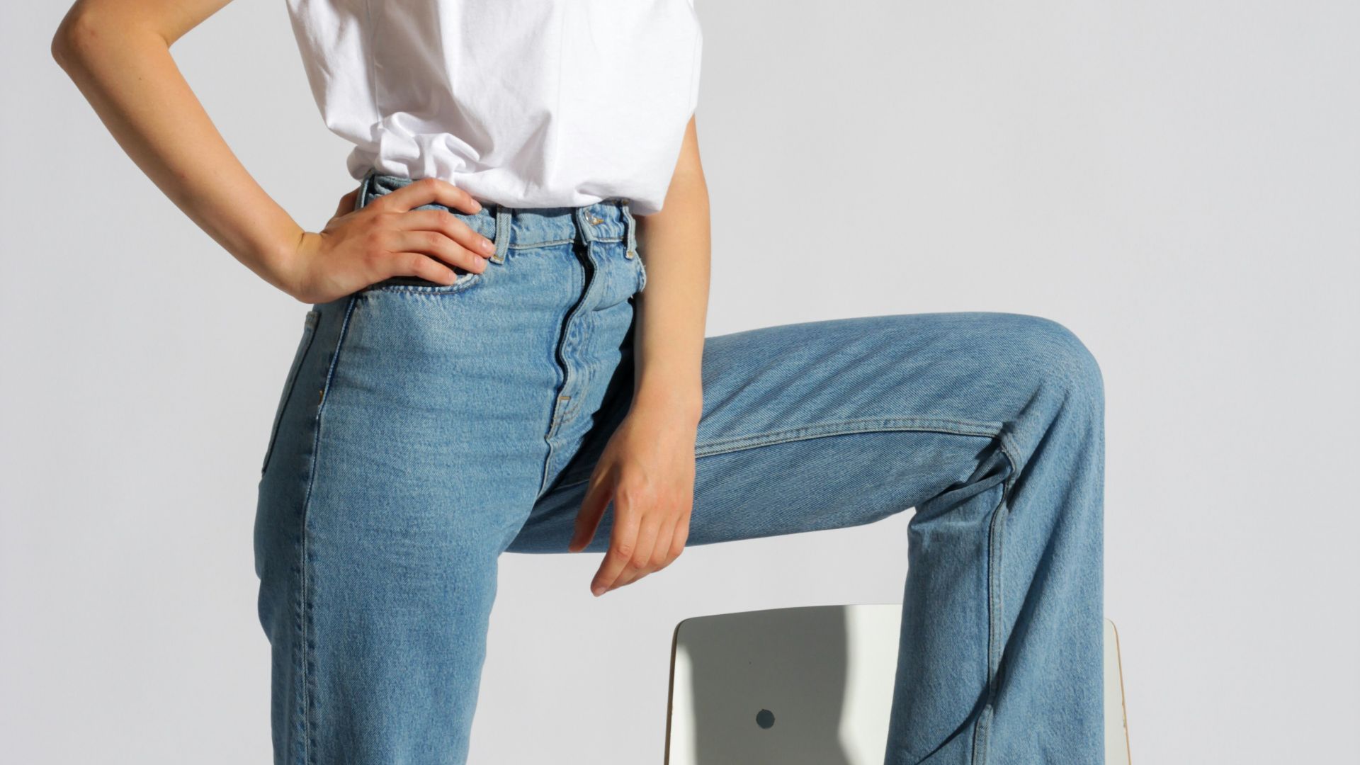 woman in white tank top and blue denim jeans sitting on white chair