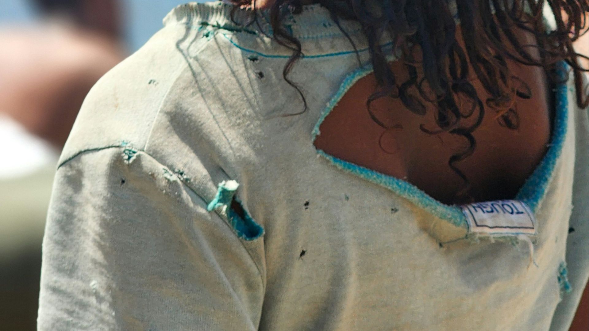 Young person with dreadlocks wearing a torn shirt