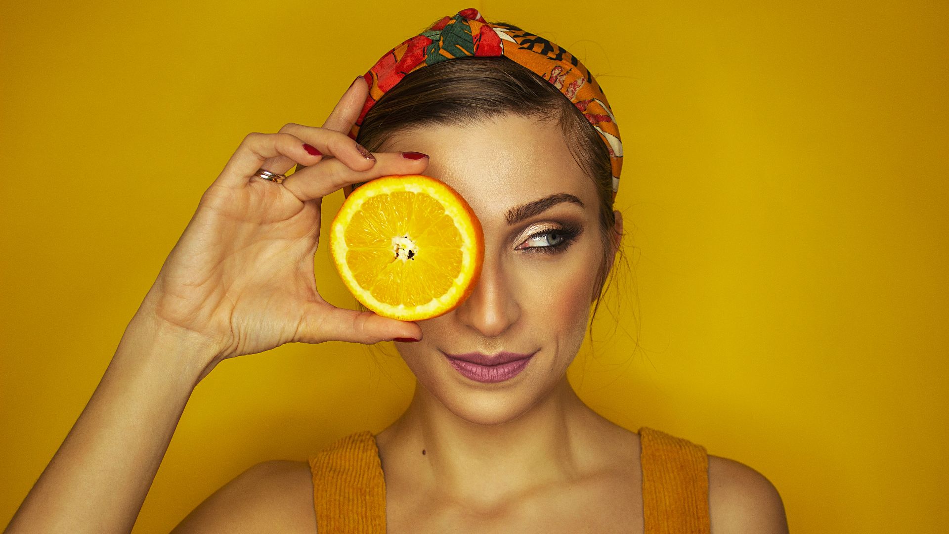 woman covering her right eye with orange slice