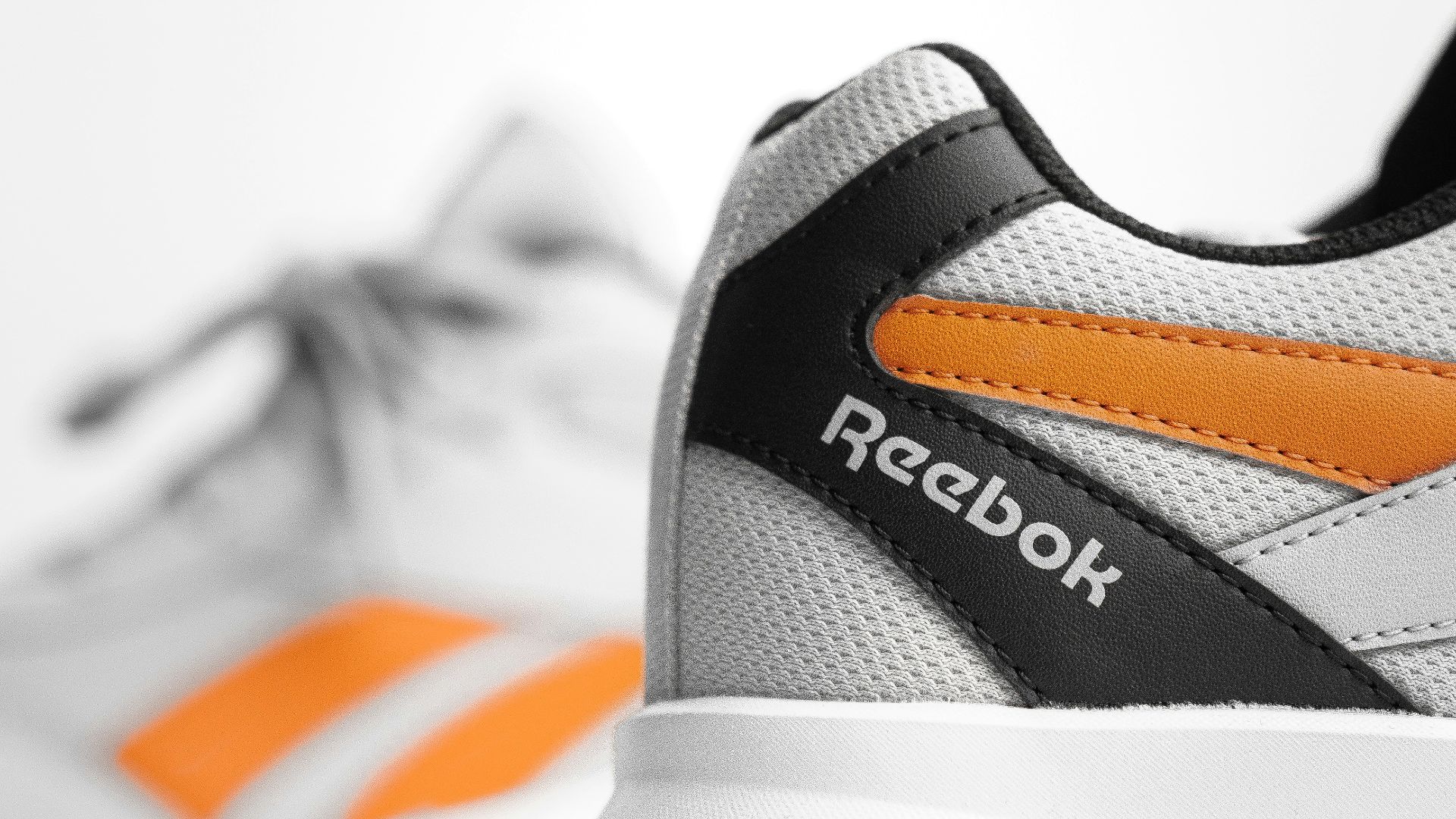 a pair of white and orange shoes on a white surface