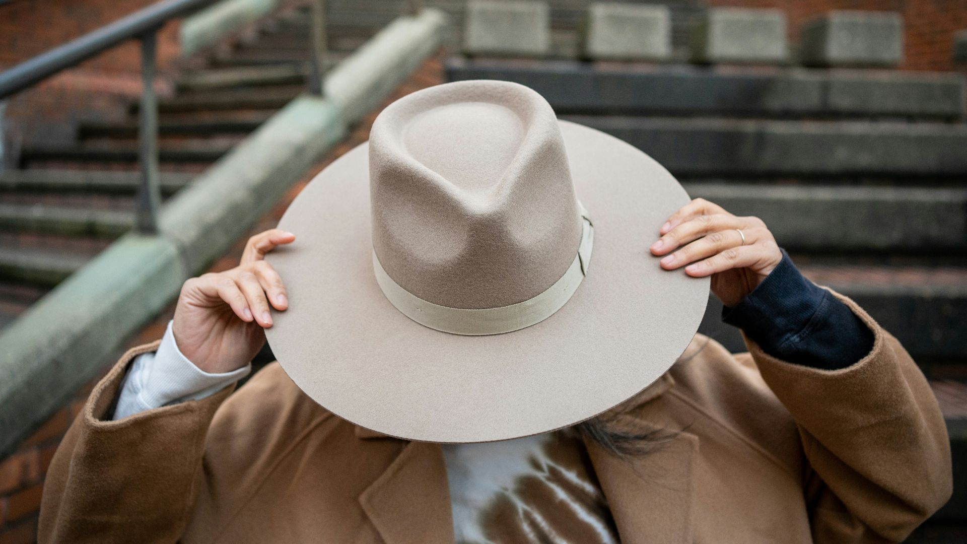 a man in a coat and hat covering his face