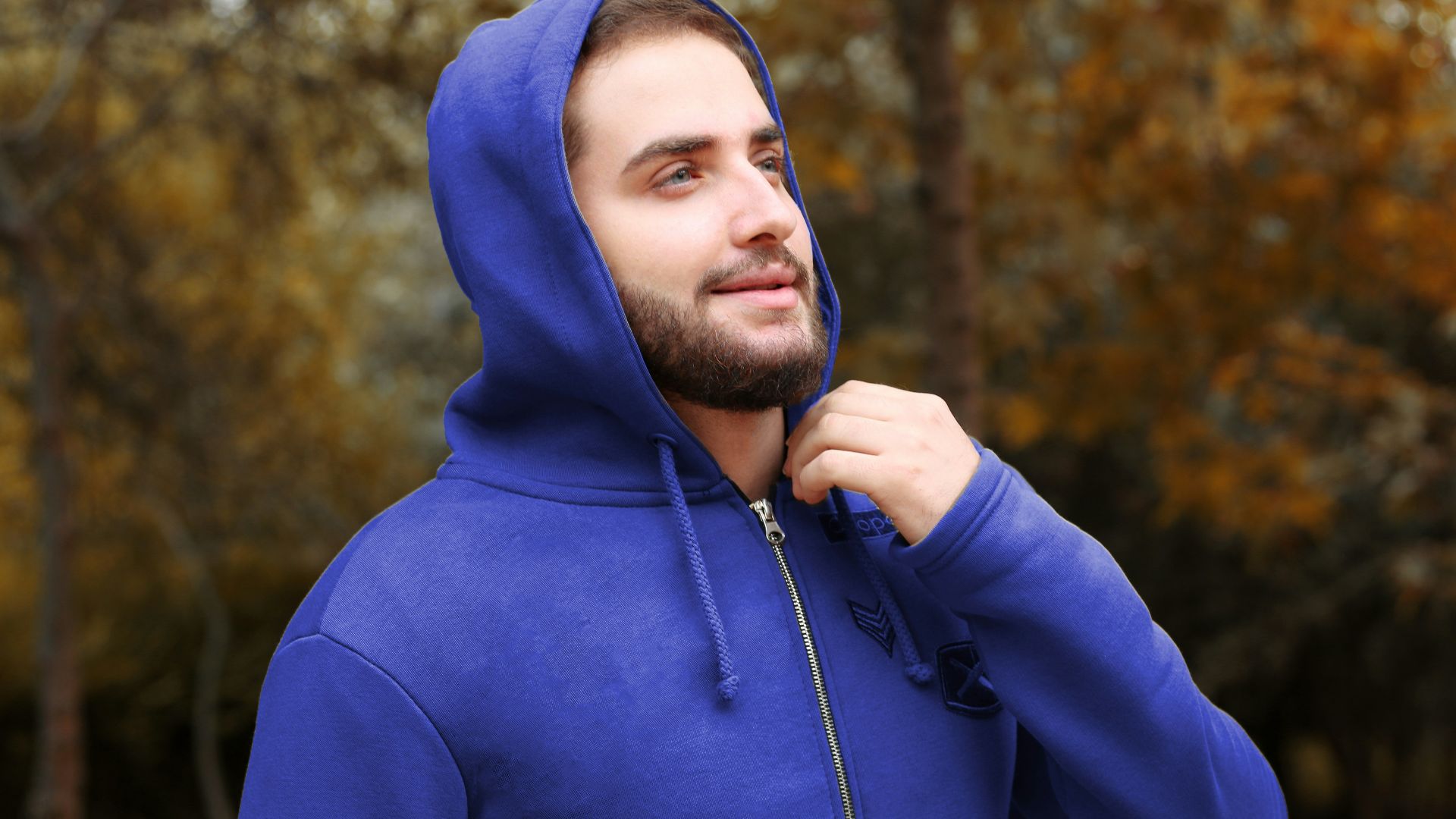 man in blue hoodie standing near trees during daytime