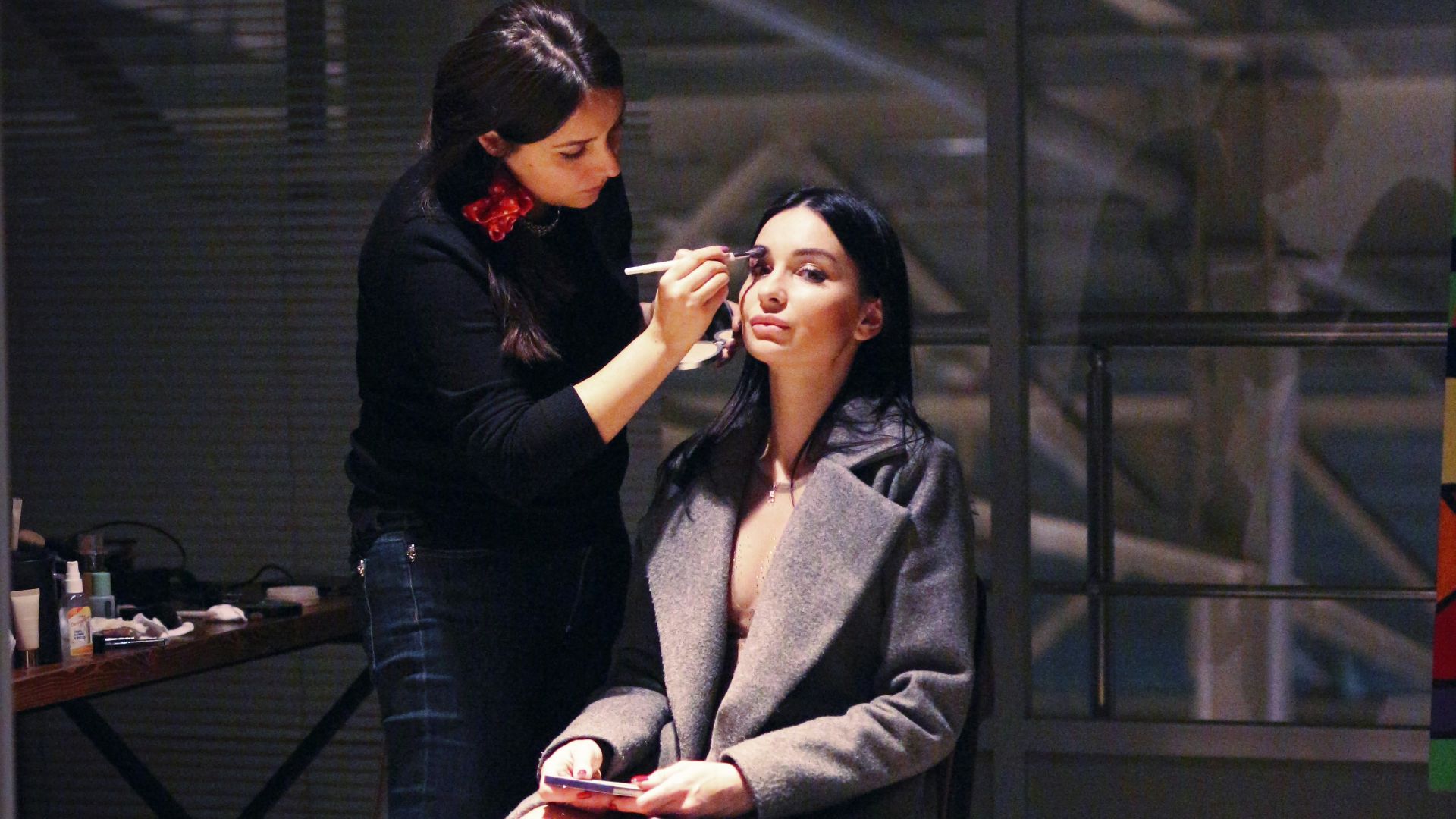 a woman getting her makeup done by another woman
