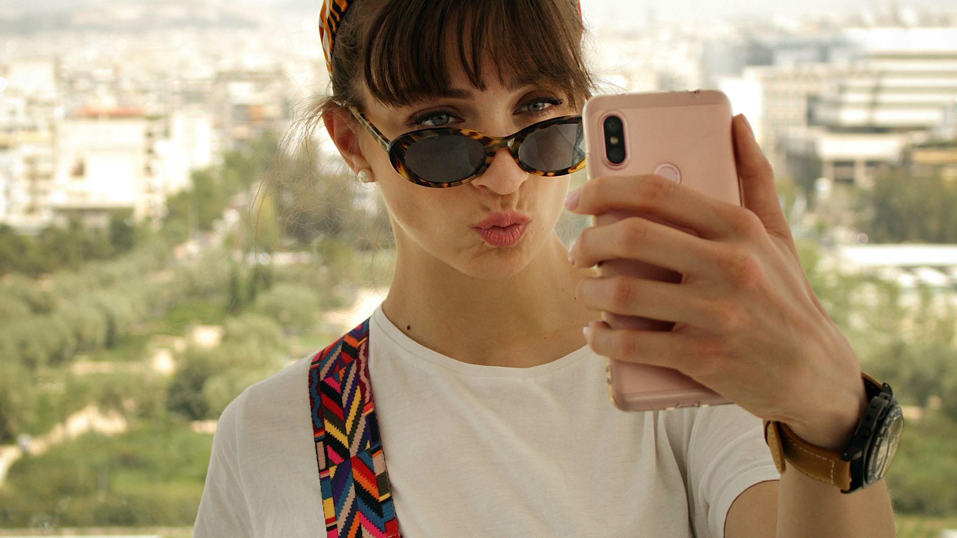 woman pouting her lips while holding smartphone in front of her face