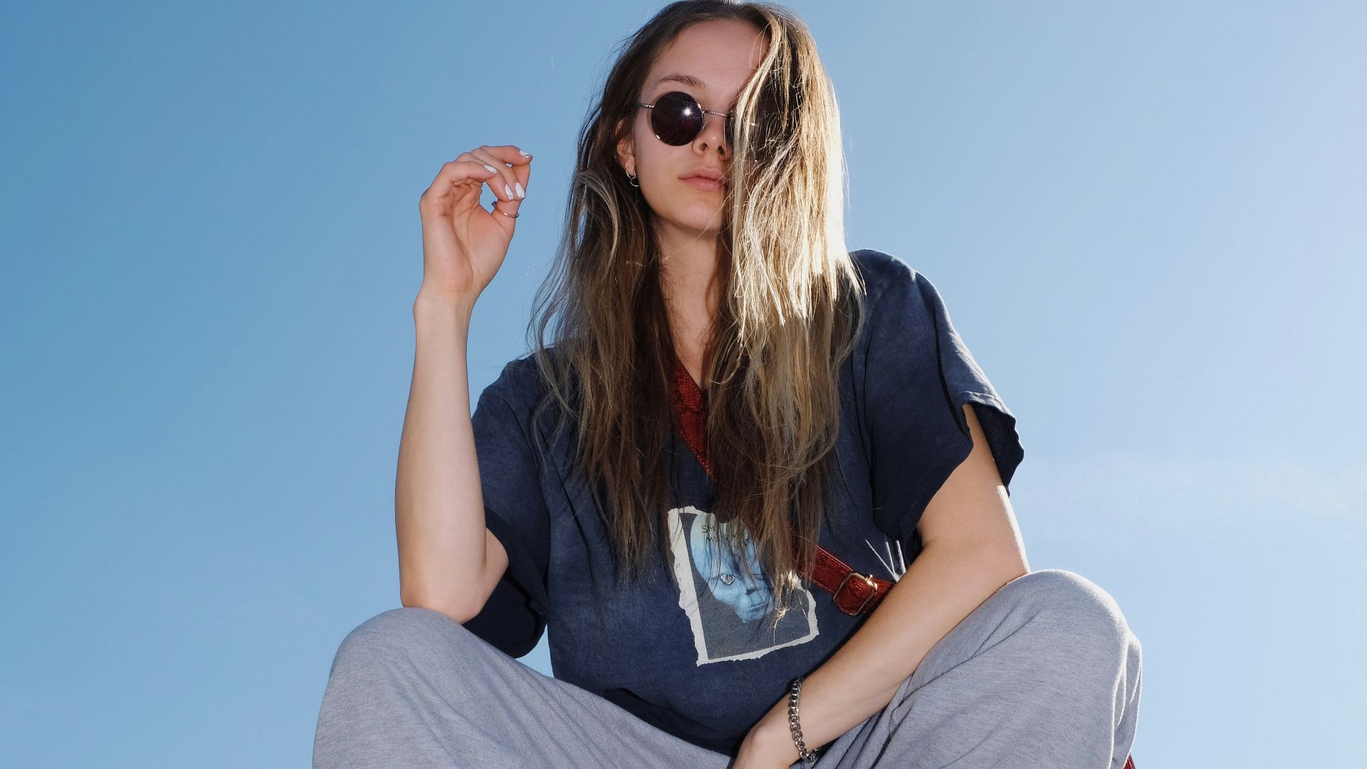 woman in black t-shirt and gray pants sitting on white metal railings during daytime