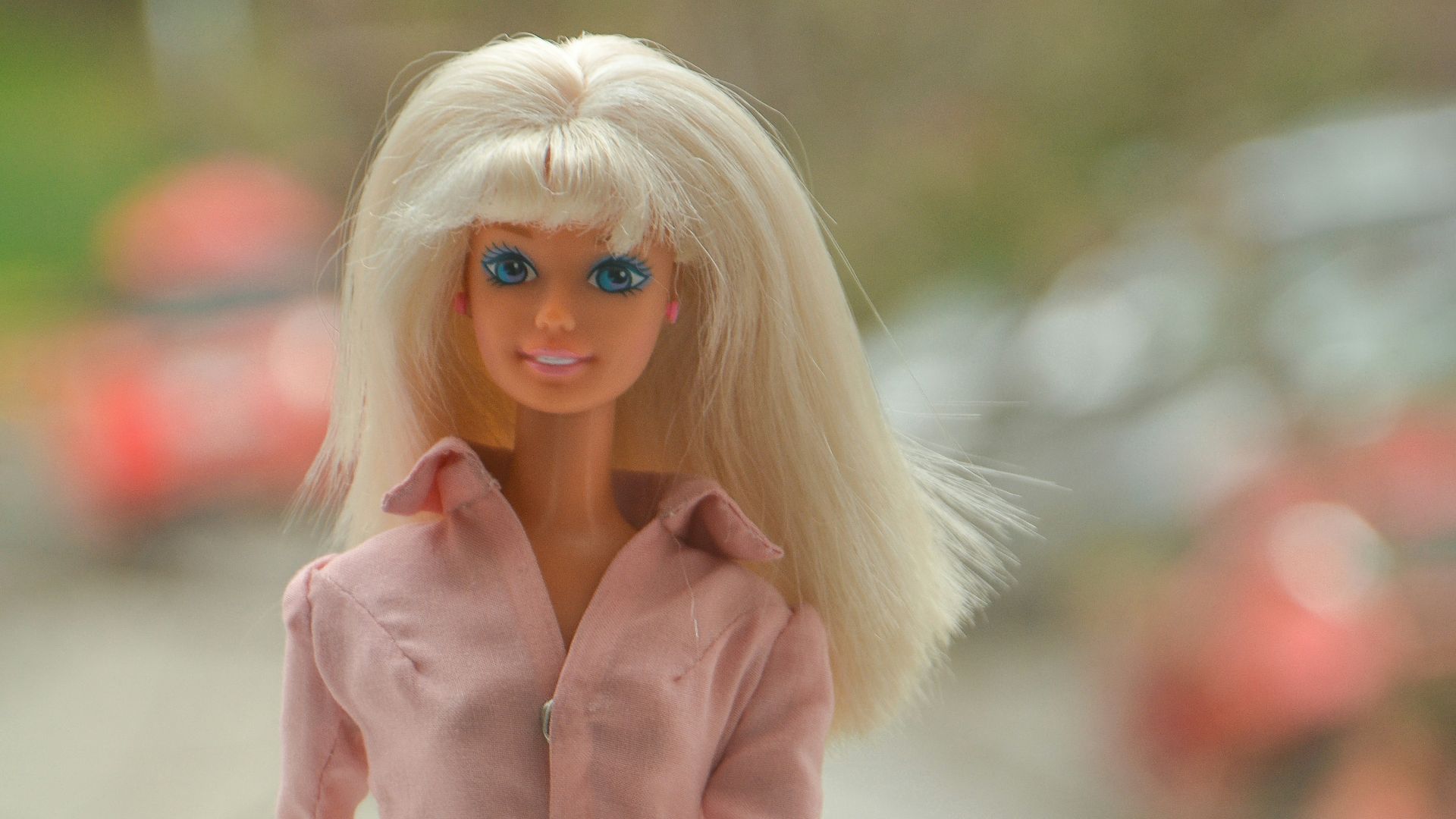 blonde haired girl in pink jacket and gray pants holding brown leather bag