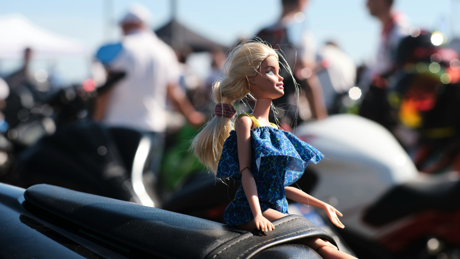 Blonde doll sits on a motorcycle seat