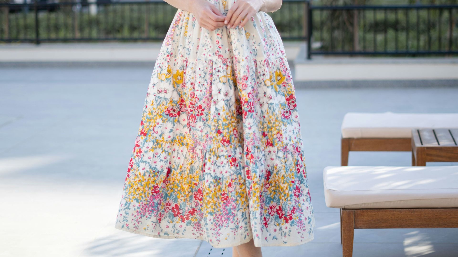 Woman in a floral sundress standing outdoors.