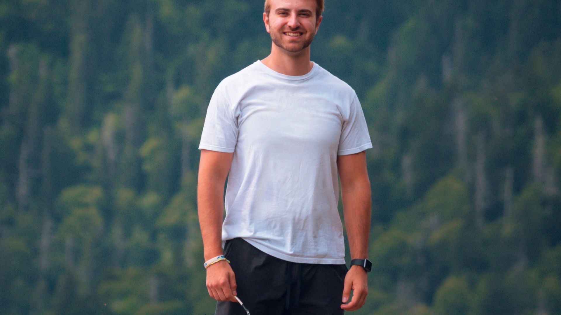 man in white crew neck t-shirt and black shorts standing on mountain during daytime