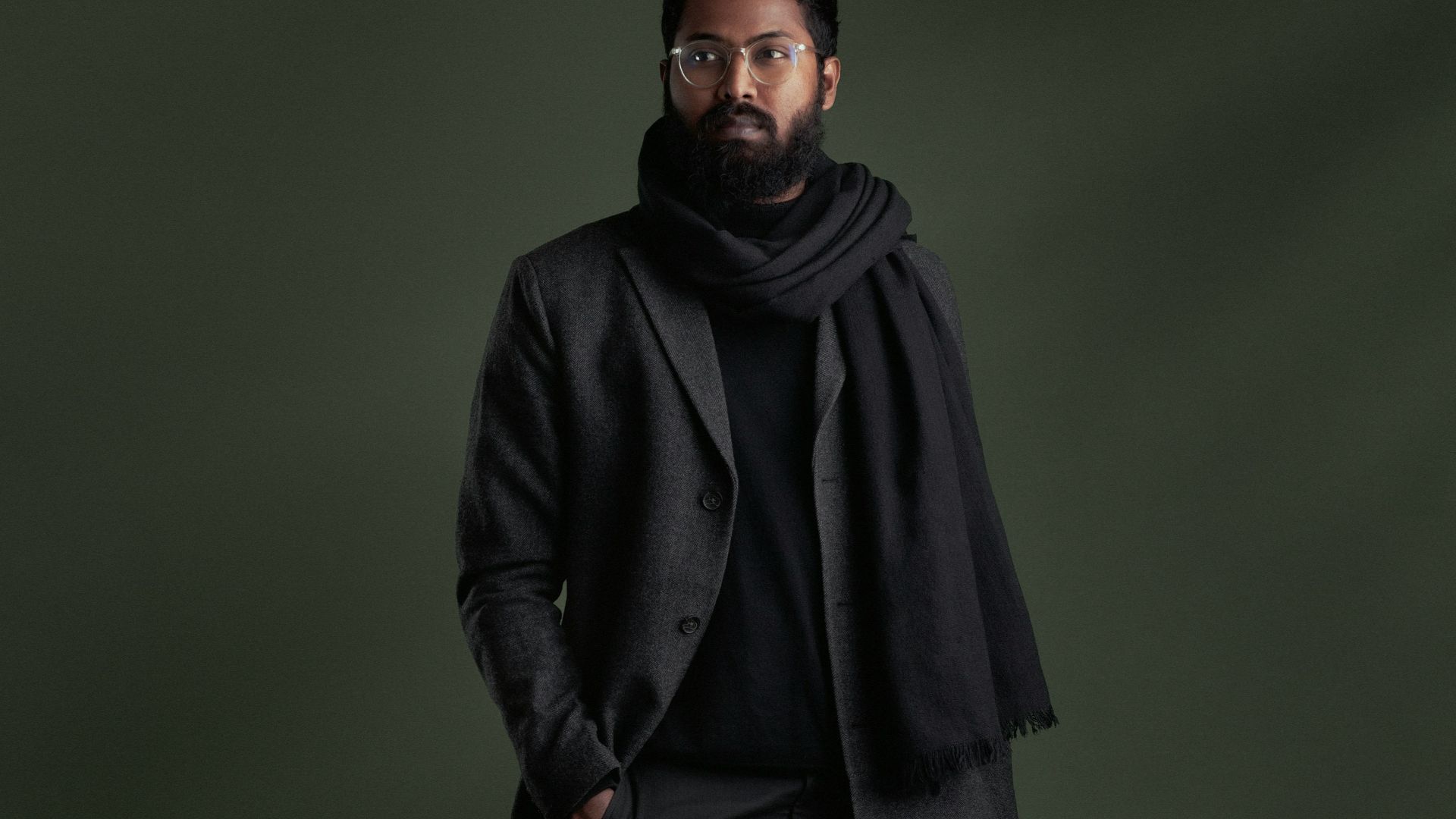 a man in a black suit and scarf