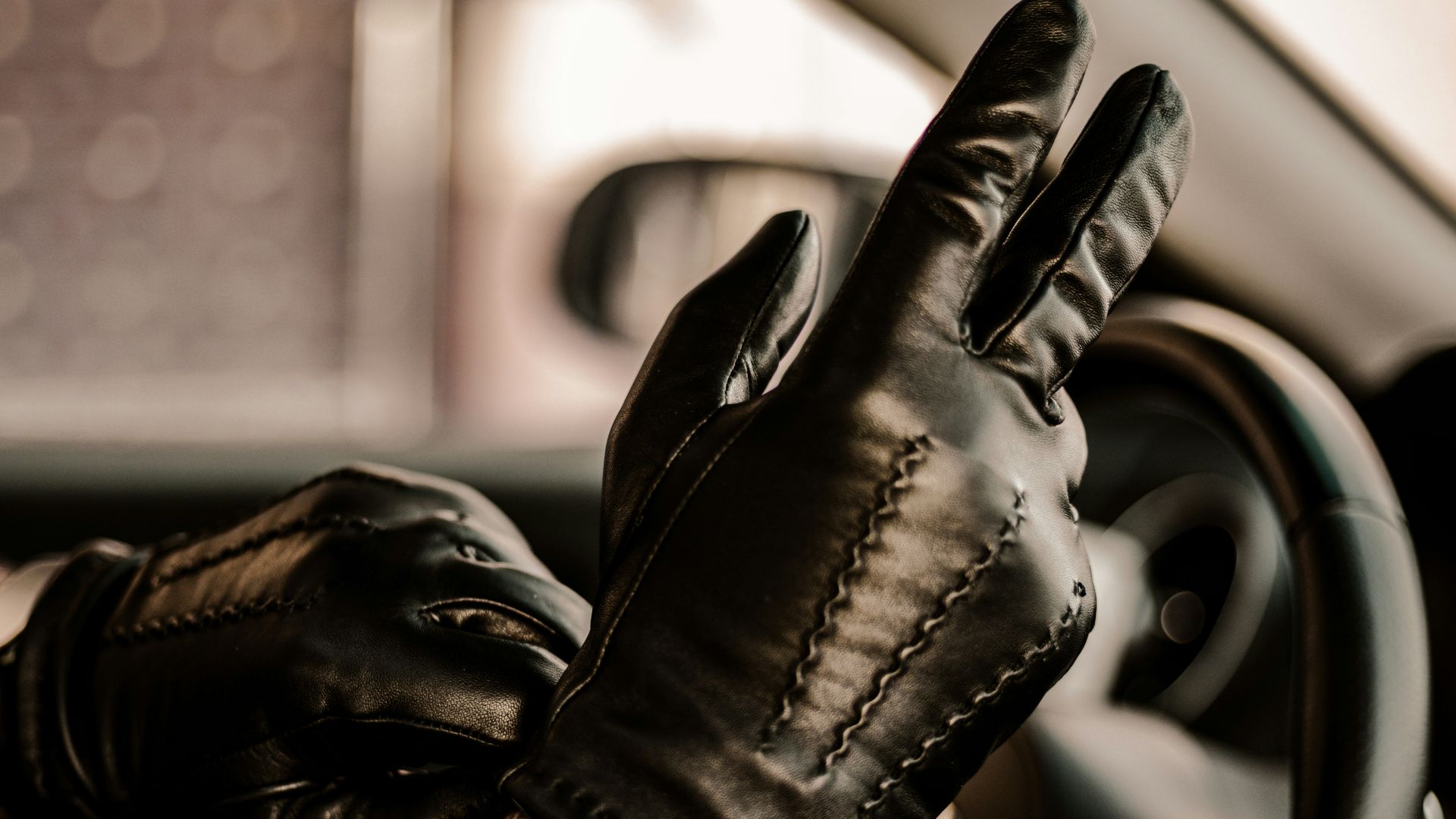 a man wearing black leather gloves driving a car