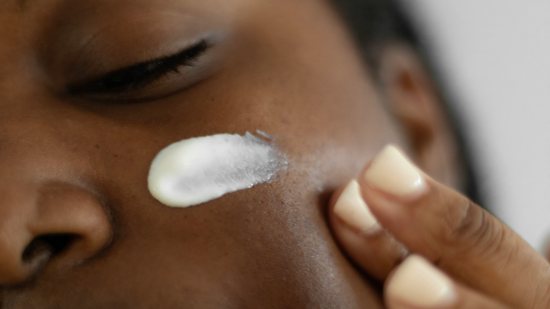 a woman is putting a lotion on her face