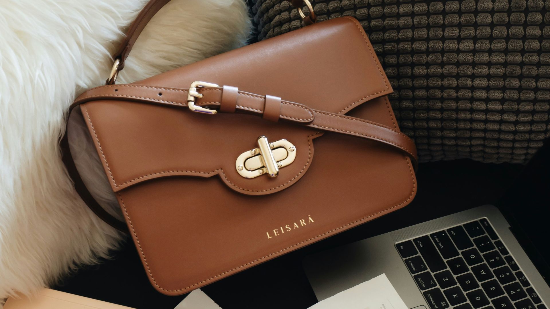 brown leather handbag beside macbook pro