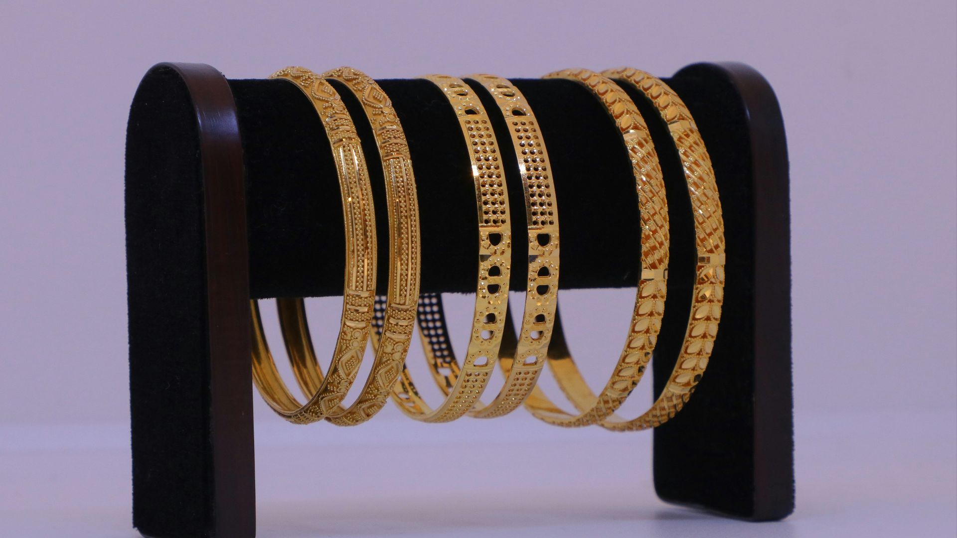 Several gold bangles displayed on a stand.