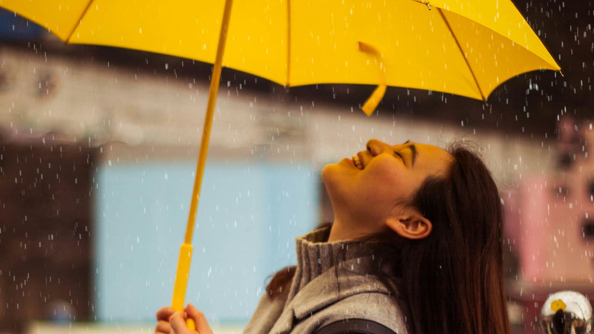 woman in gray jacket holding yellow umbrella