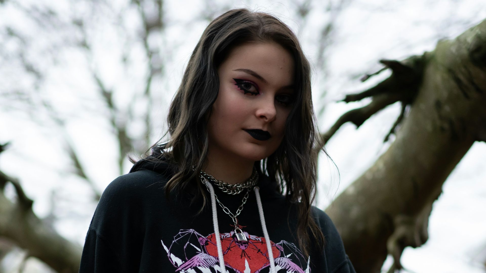 woman in black and white long sleeve shirt sitting beside brown tree during daytime