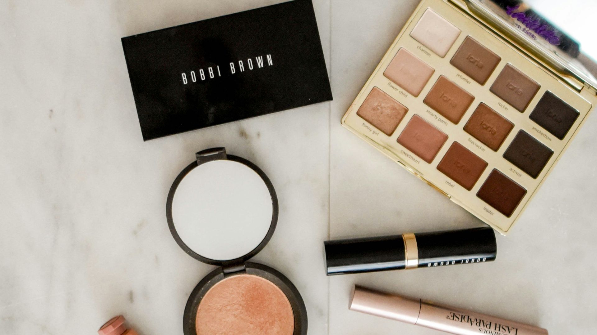 photo of assorted makeup products on gray surface