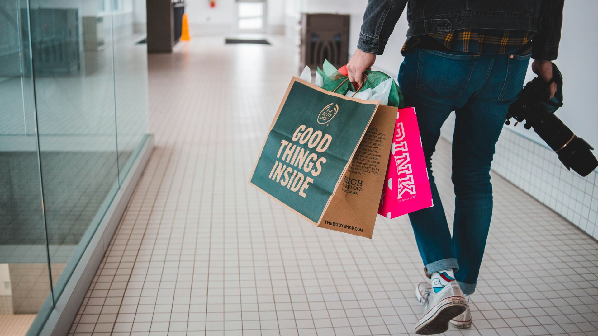 person walking while carrying a camera and paper bags