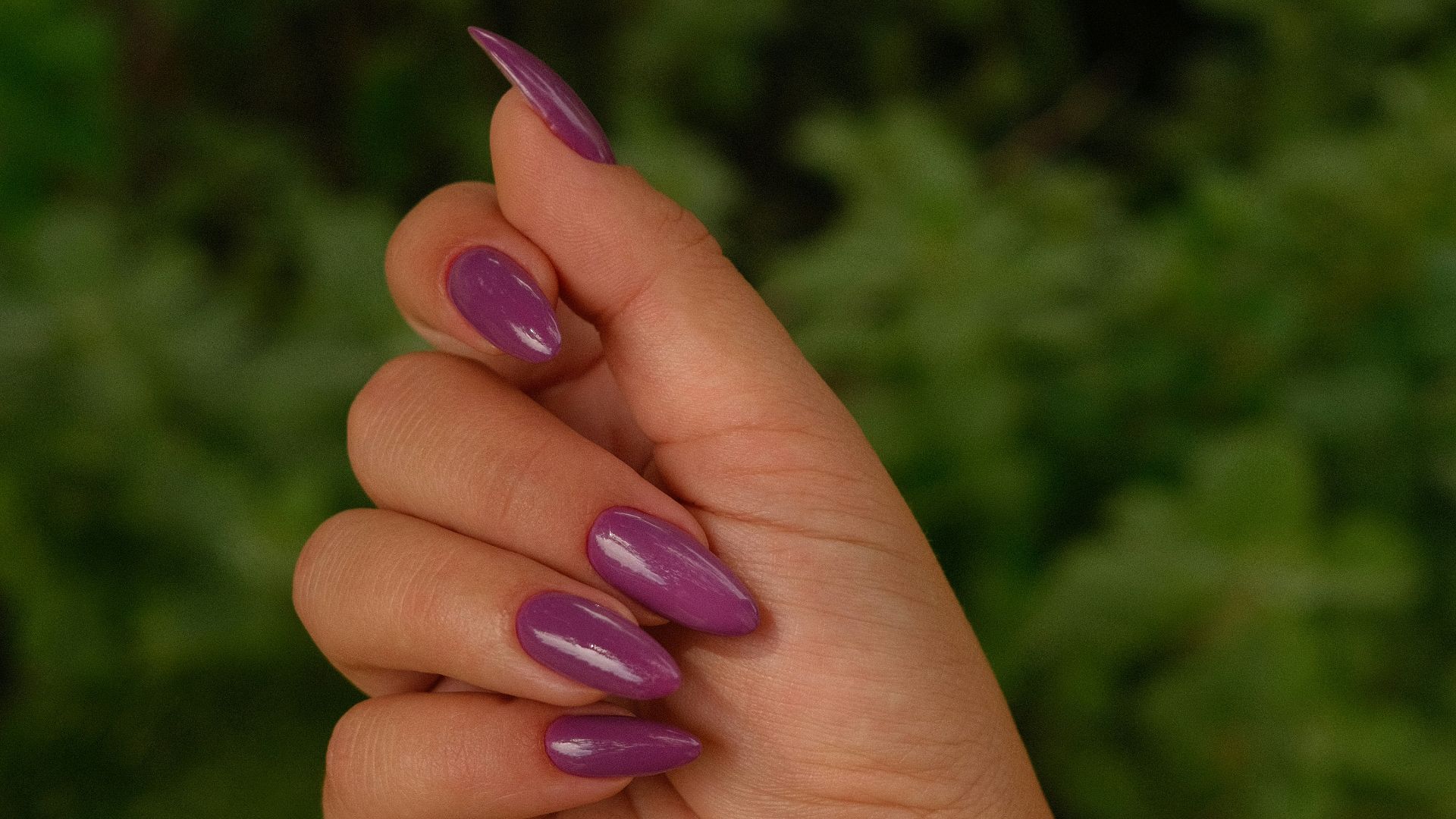 A hand displays painted purple nails.