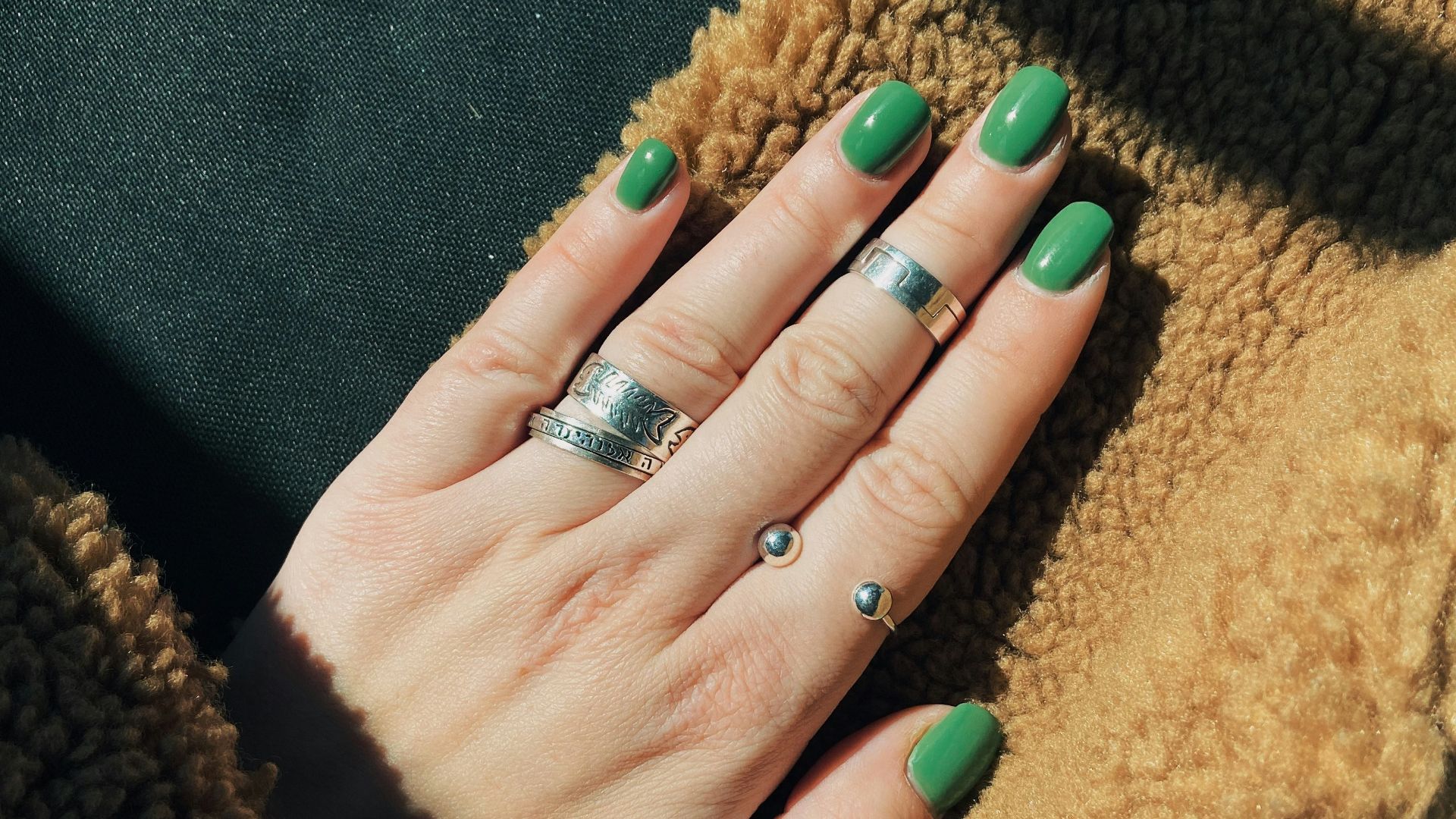 person wearing silver ring with green manicure