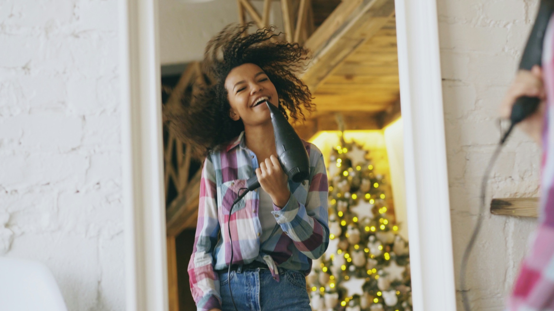 Young woman singing into hairdryer in front of mirror