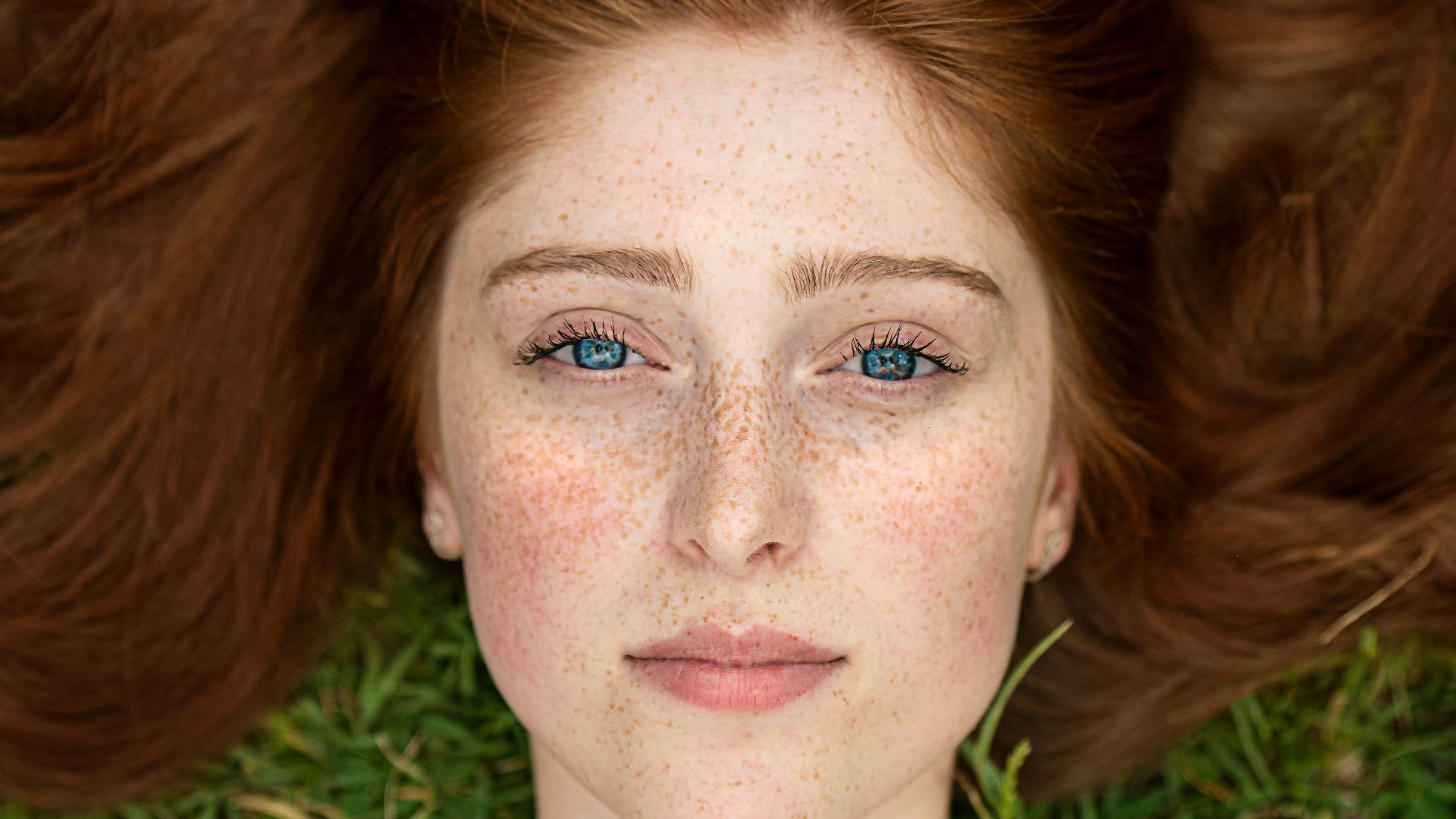 woman in green shirt lying on brown grass