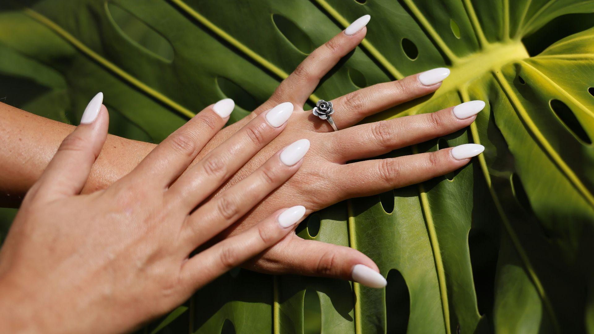 a woman's hands with white manicures and a ring