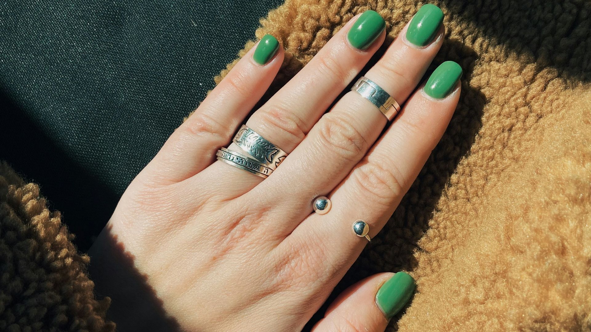 person wearing silver ring with green manicure
