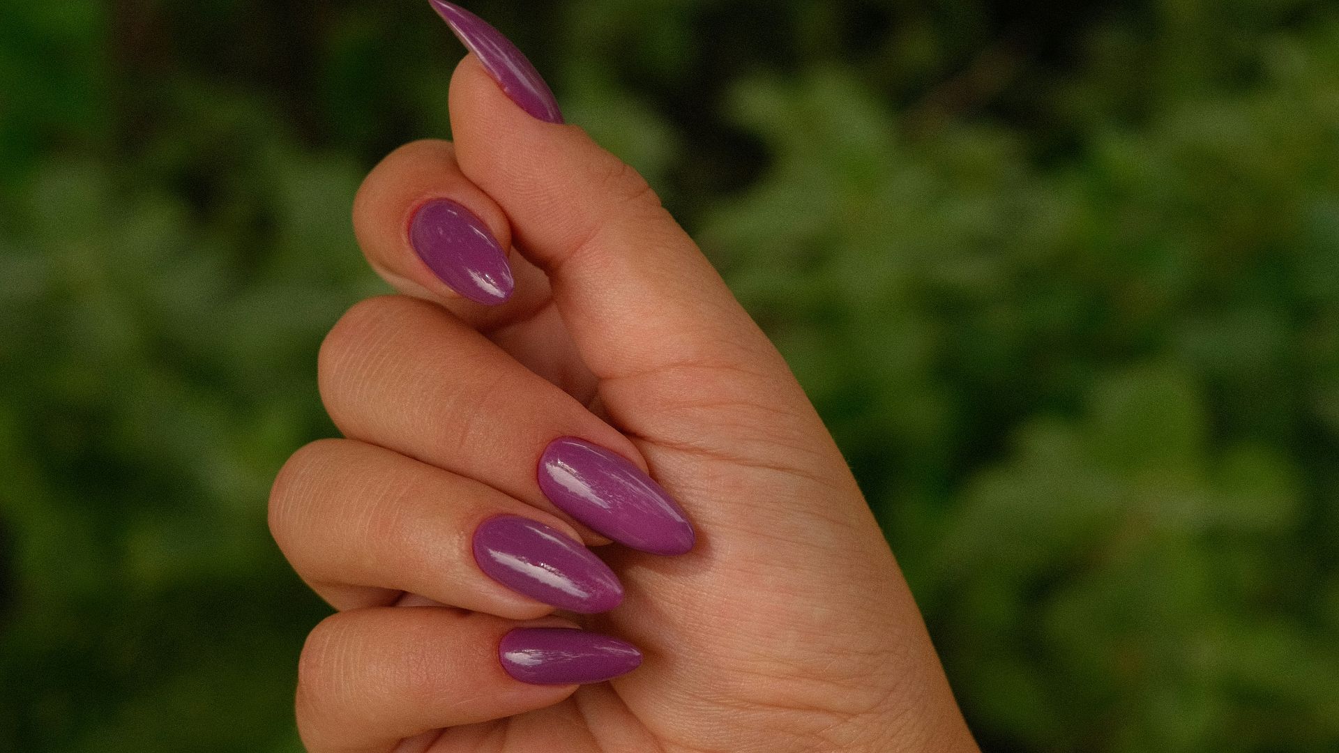 A hand displays painted purple nails.