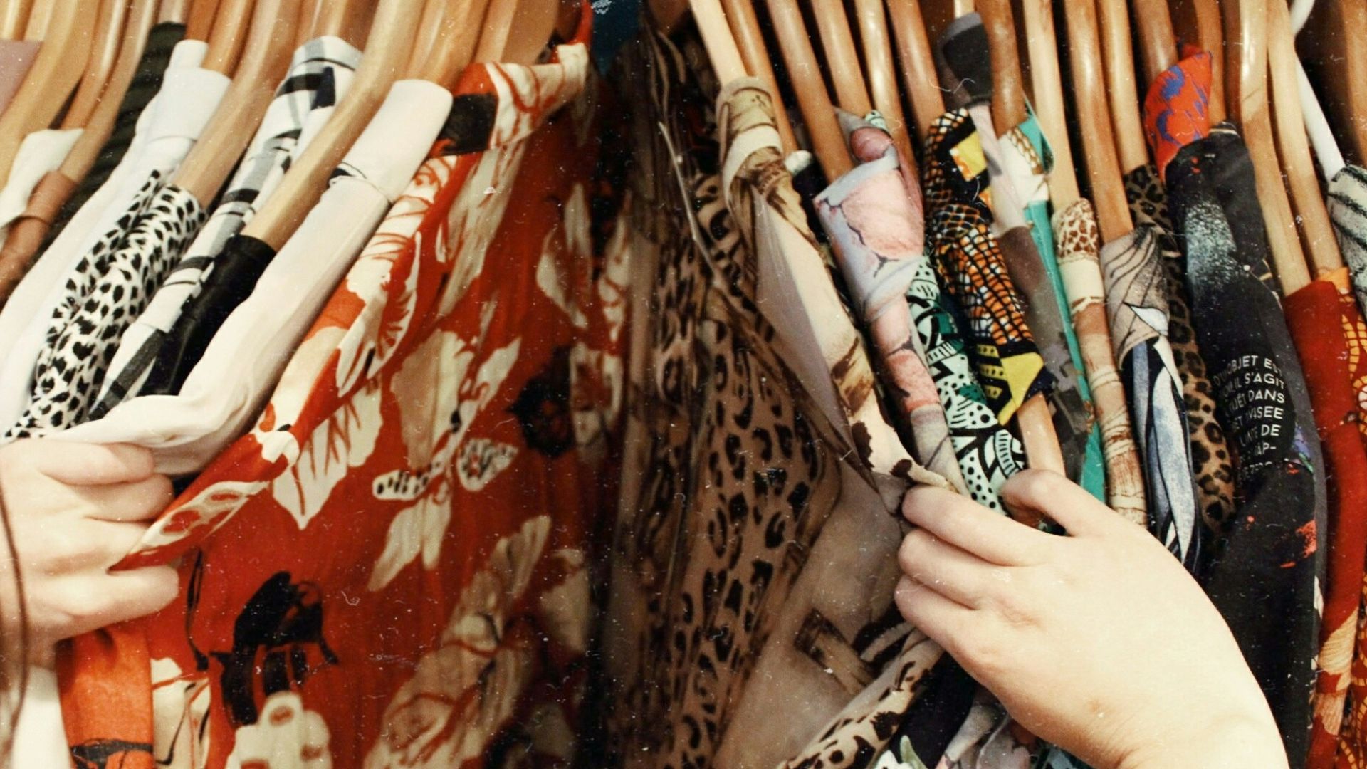 person holding assorted clothes in wooden hanger