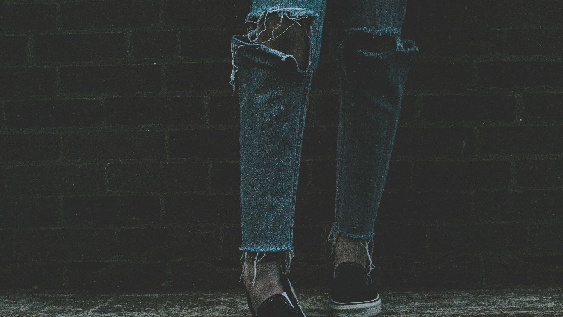 person wearing distressed blue denim jeans and pair of black-and-white sneakers
