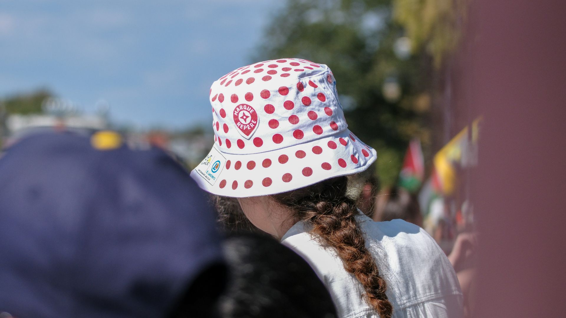 Person wearing a white bucket hat with red dots.