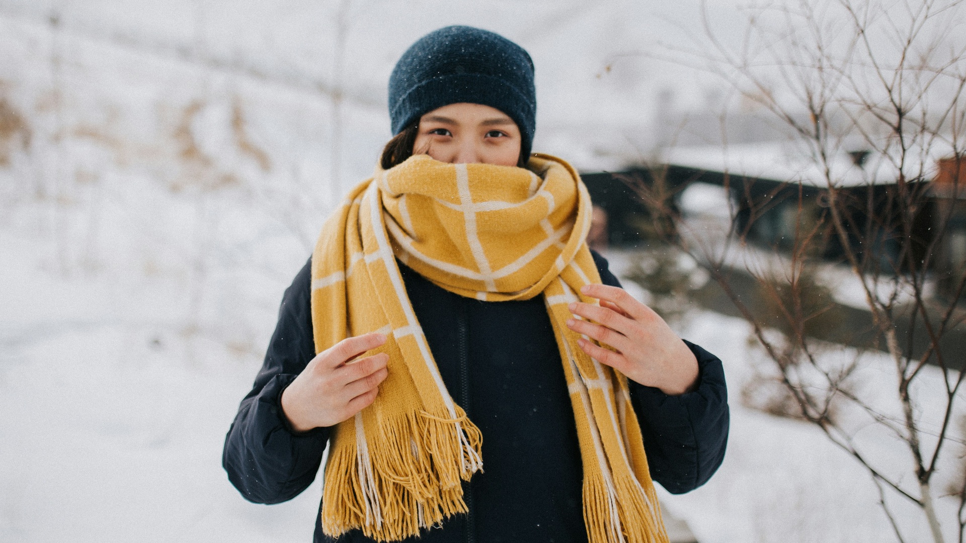 woman in black knit cap and black jacket standing on snow covered ground during daytime