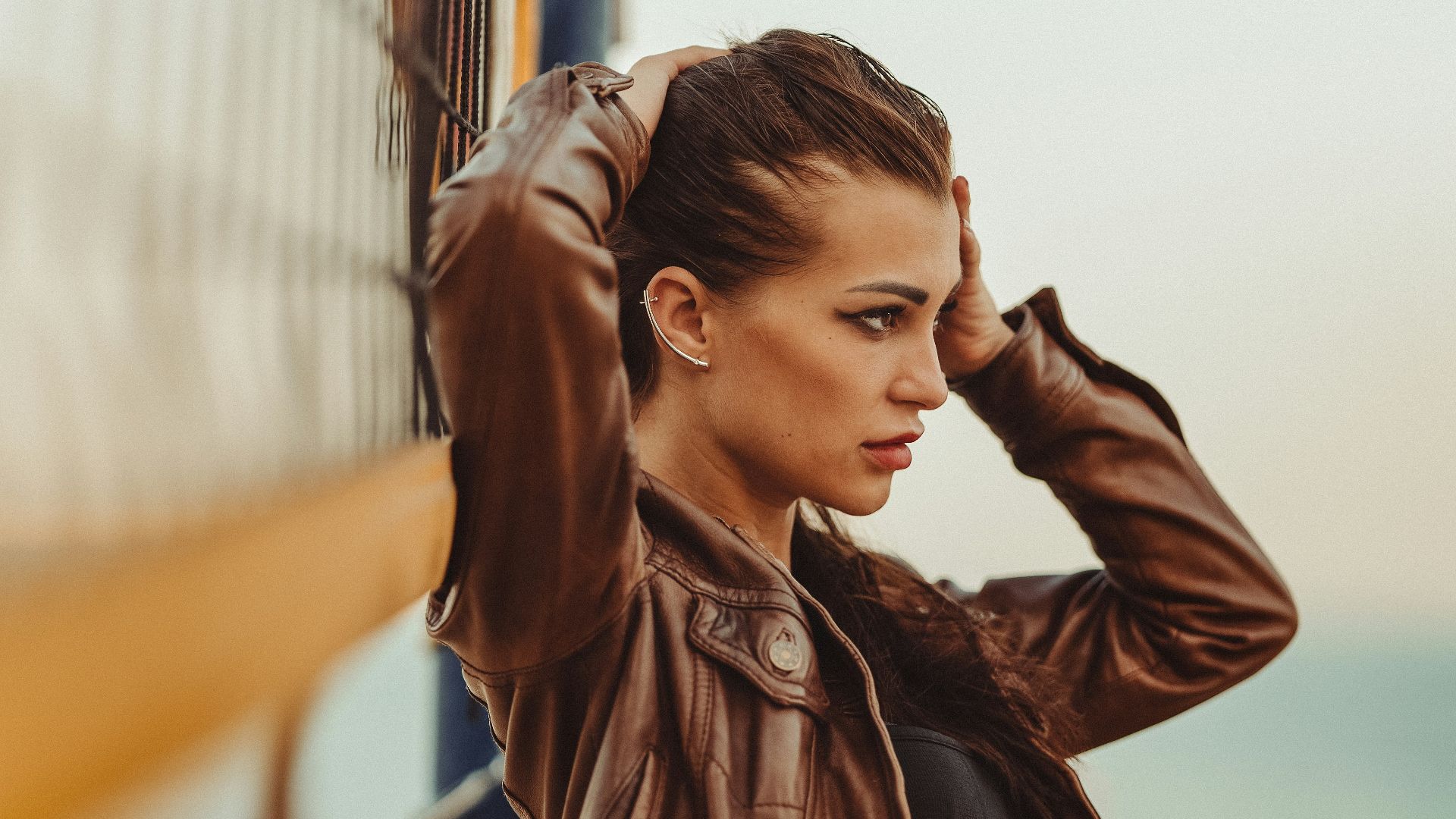 a woman in a leather jacket leaning against a volleyball net