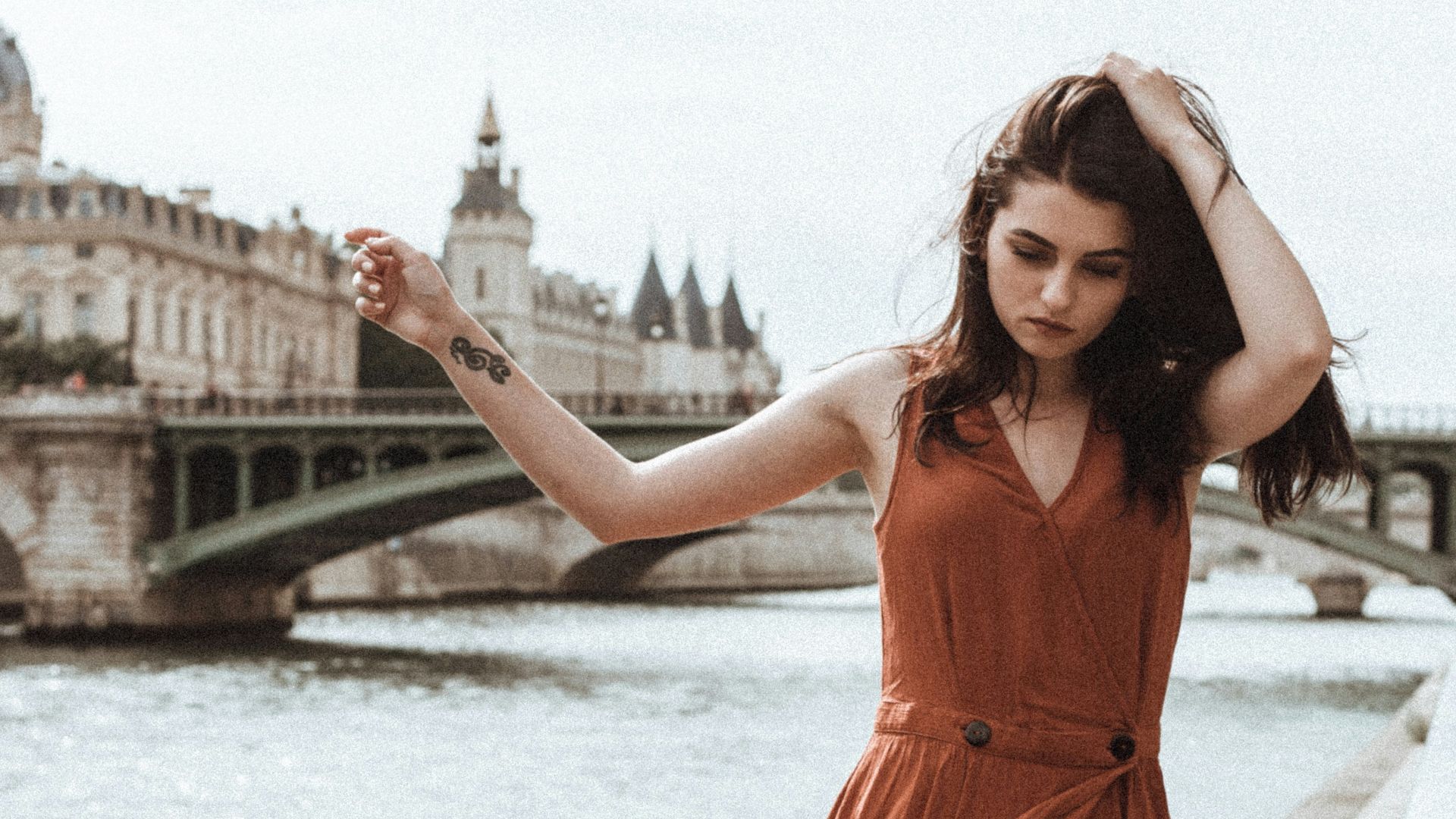 woman in red sleeveless dress standing on bridge during daytime