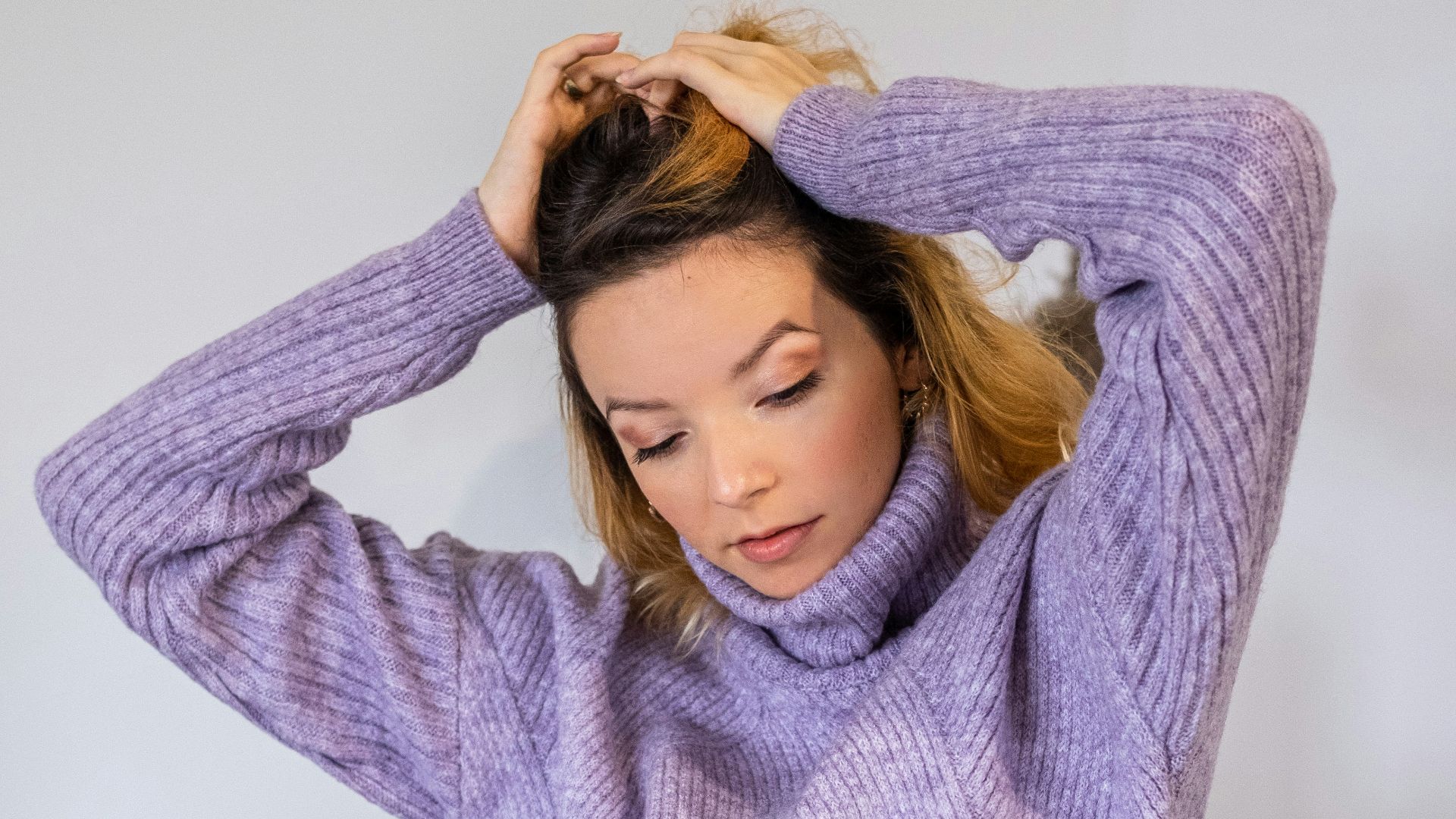 a woman sitting on a chair with her hands on her head