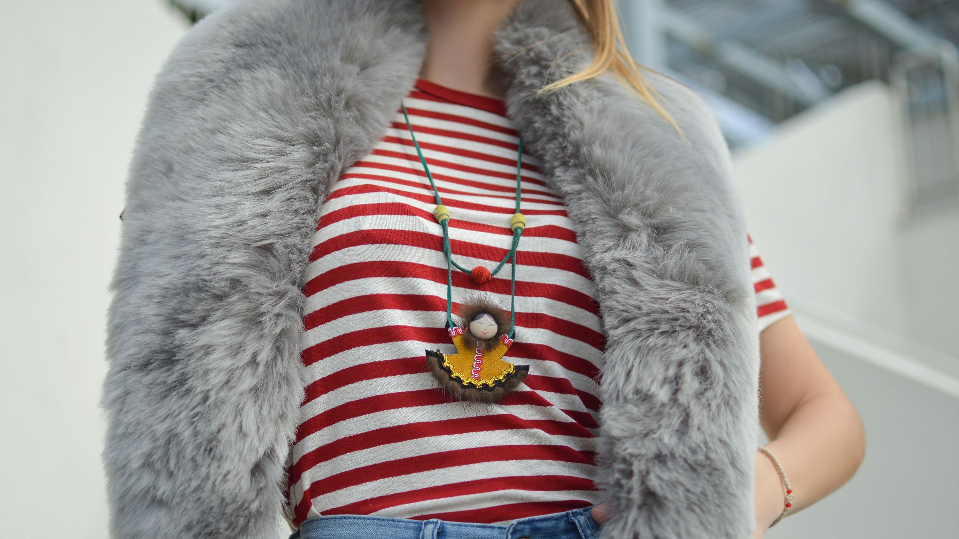 woman wearing red and white striped crew-neck t-shirt and blue denim bottoms outfit with gray faux fur scarf at daytime