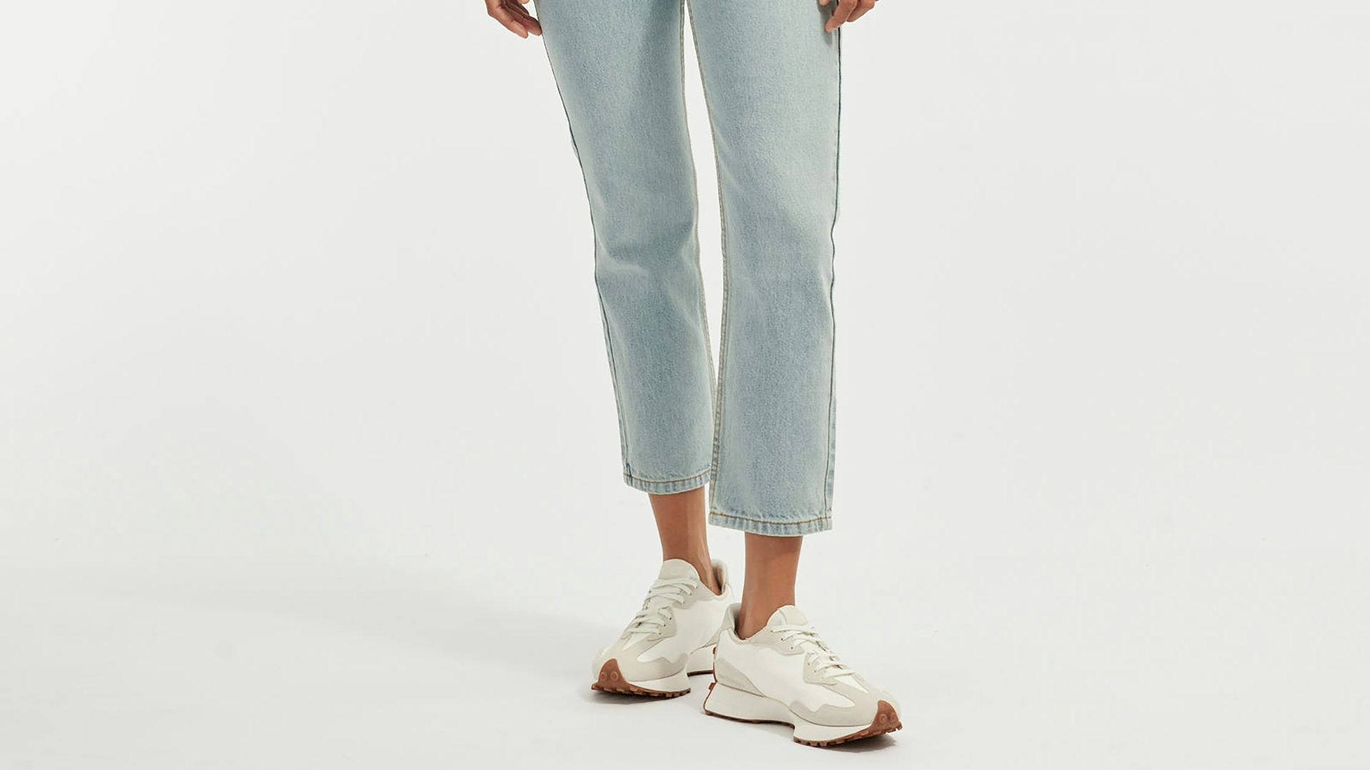 Woman wearing a light gray sweatshirt and light blue jeans.