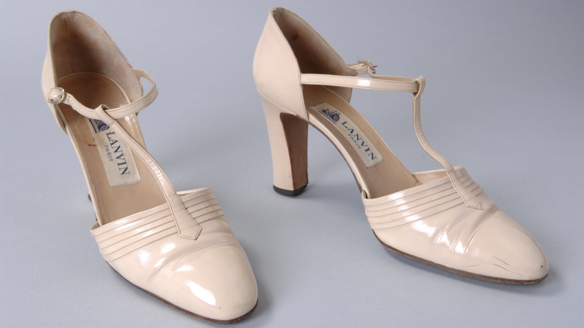 File:Ivoorwitte lakleren T-bandschoen met plooidecoratie over de voorvoet en zeer smalle bandjes, smalle hoge blokhak, objectnr 69386-1-2.JPG