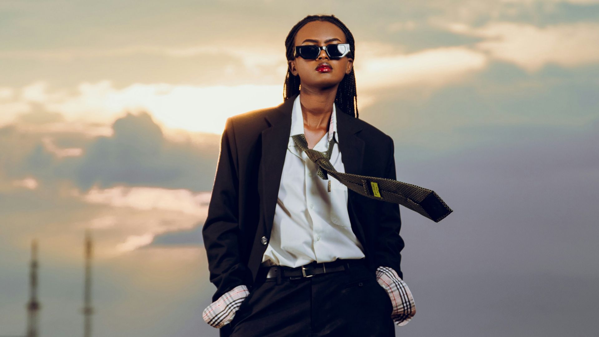 Person in suit with sunglasses on rooftop at sunset
