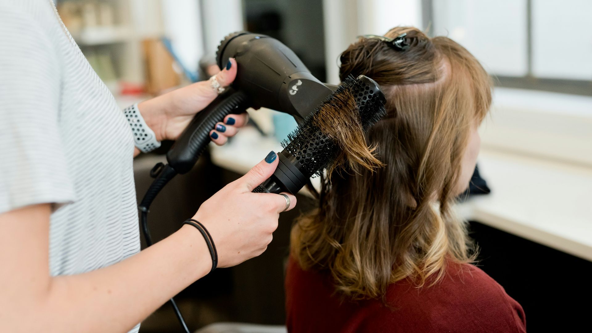 woman in red long sleeve shirt holding hair blower