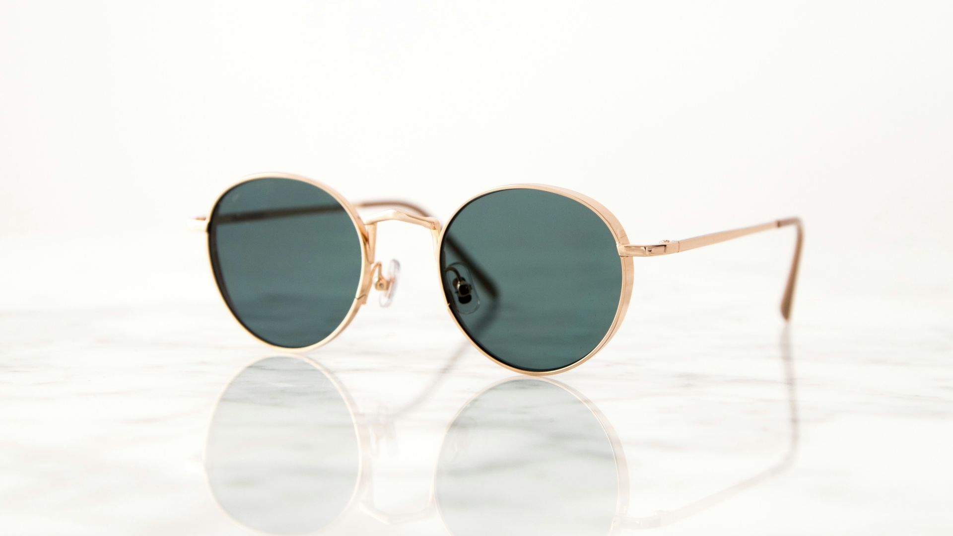 gold-colored framed hippie sunglasses on white surface