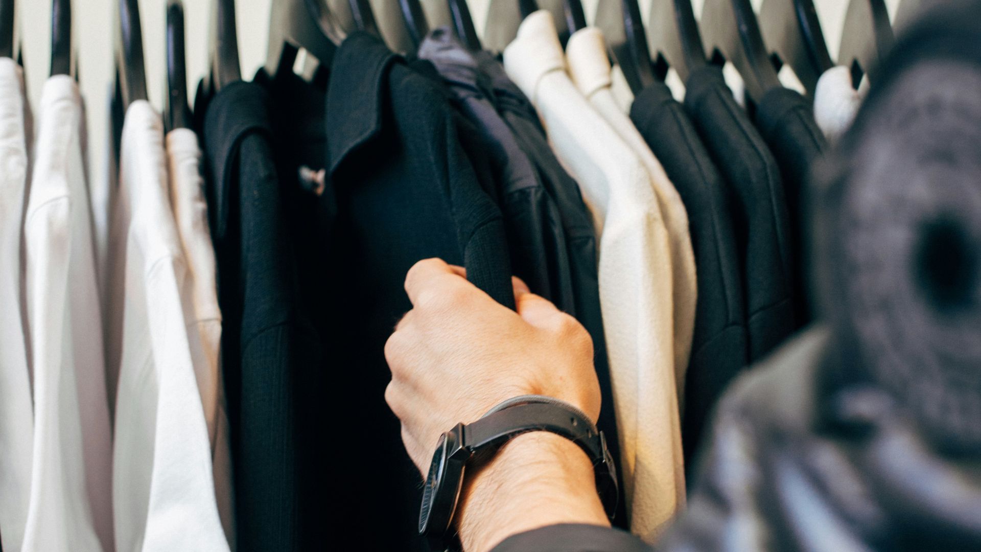 person holding hanged black shirts