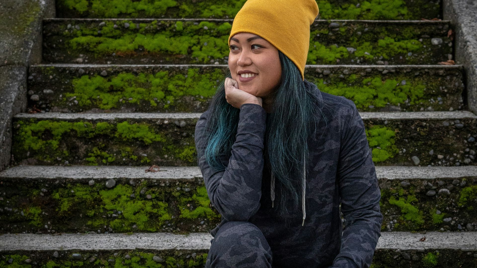 boy in black jacket and yellow knit cap sitting on concrete stairs