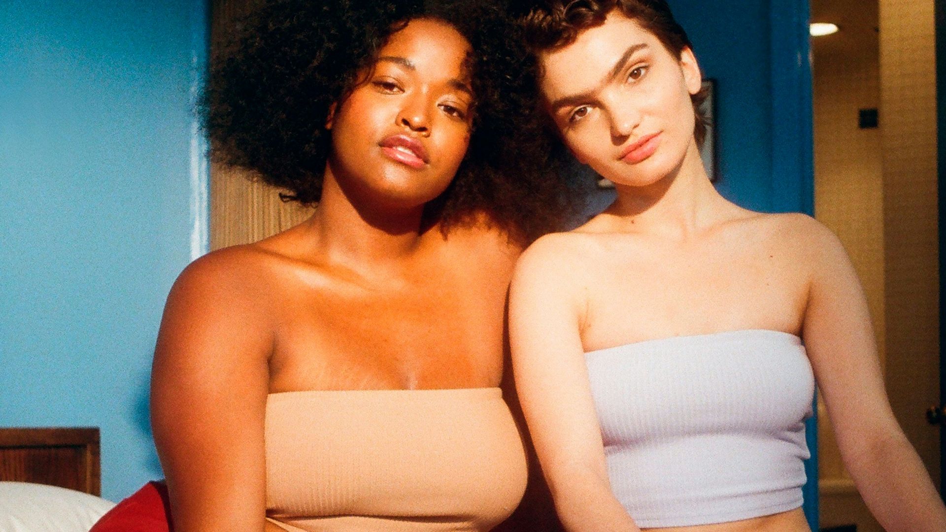 two woman sitting on bed inside room