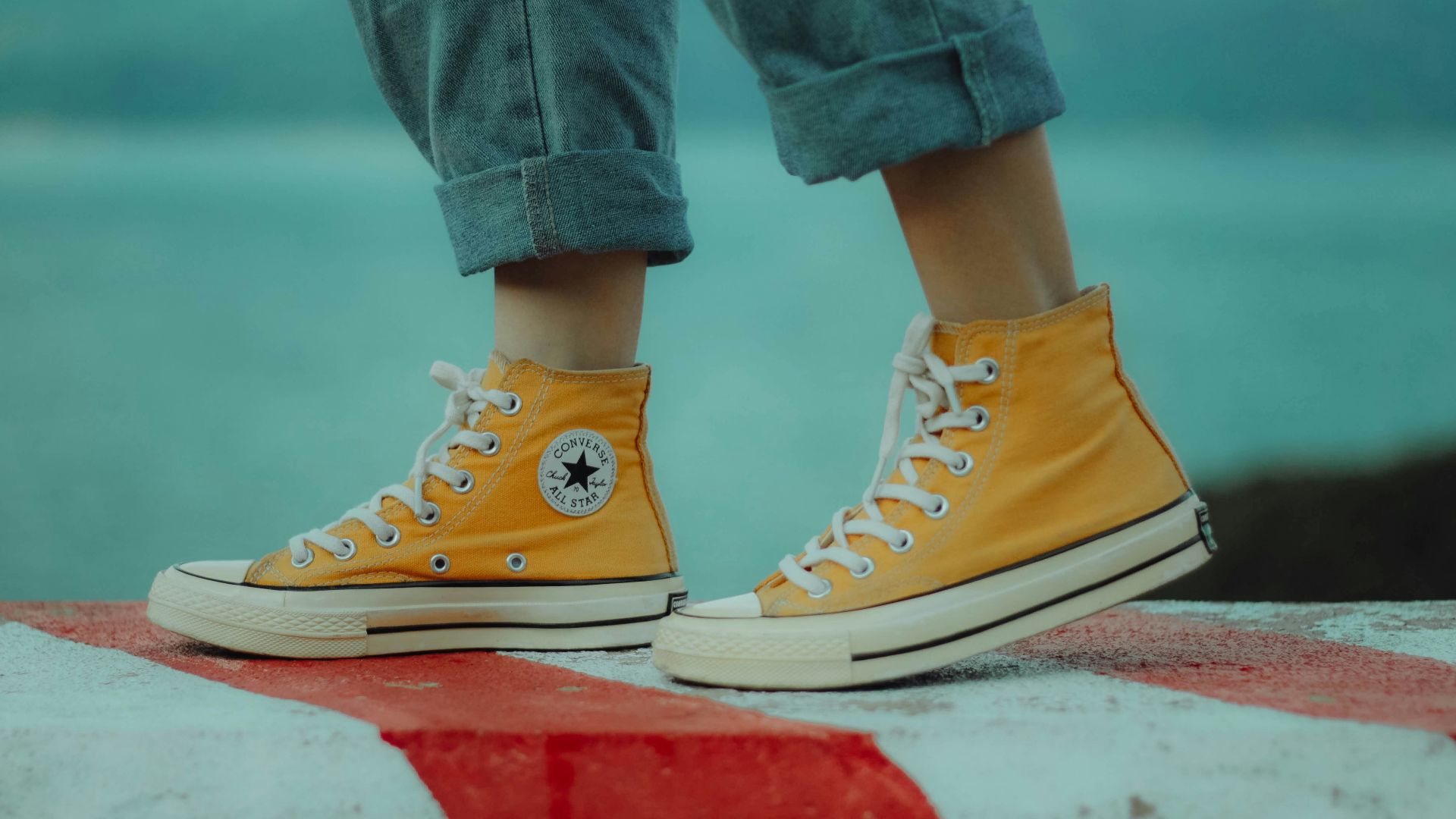 person wears yellow orange Converse All-Star high-top sneakers